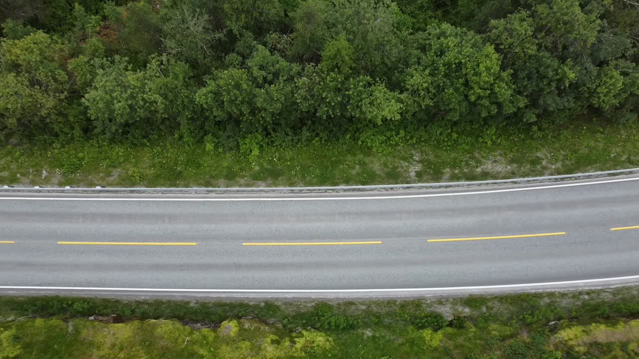 vista de arriba hacia abajo sobre un coche blanco que pasa por un lago en noruega