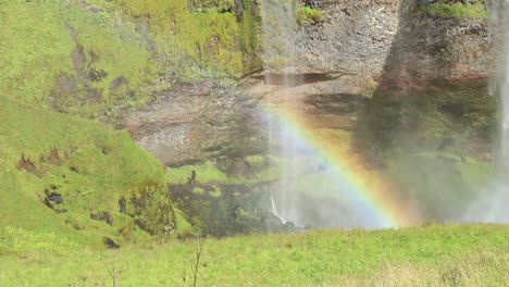 A-view-at-seljalandfoss,-icelandic-waterfall-where-it-hits-the-ground-and-you-can-see-the-appearance-of-a-rainbow