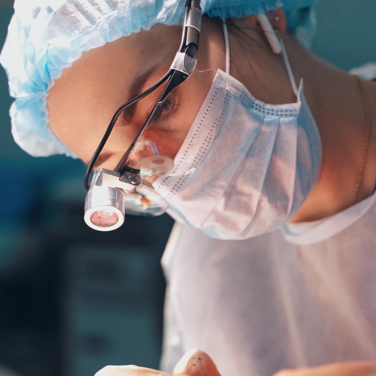 Portrait of a female doctor in surgical mask. Professional specialist looking down while performing a plastic surgery. Close-up.