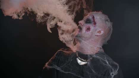 Zombie-man-with-makeup-with-wounds-scars-and-white-contact-lenses-blows-smoke-from-nose-and-mouth