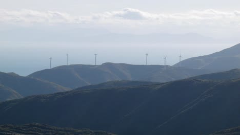 a group of wind turbines on a hill overlooking the ocean