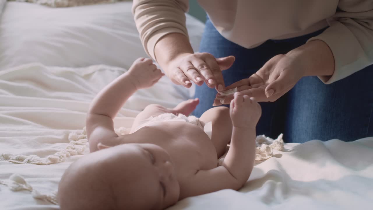 Mother applying moisturizing balm on baby's body