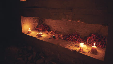 candles illuminating an ancient stone shrine with offerings at night