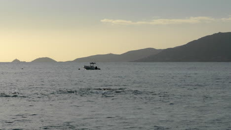 Escena-Tranquila-Del-Océano,-Barco-Anclado,-Montañas-De-Fondo-Al-Atardecer