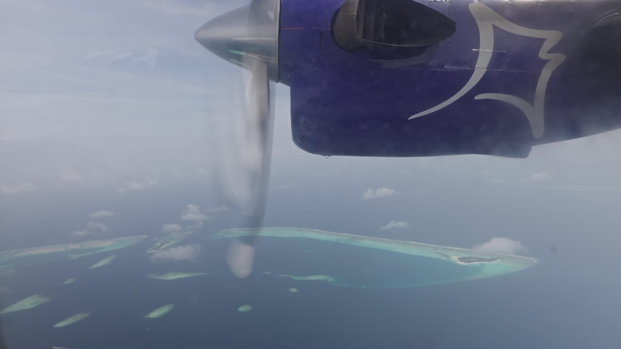 vista por la ventana del motor de un avión giratorio con una isla tropical debajo