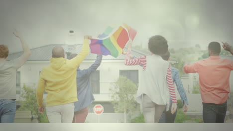 grupo diverso de personas sosteniendo una bandera arco iris mientras caminan hacia el edificio