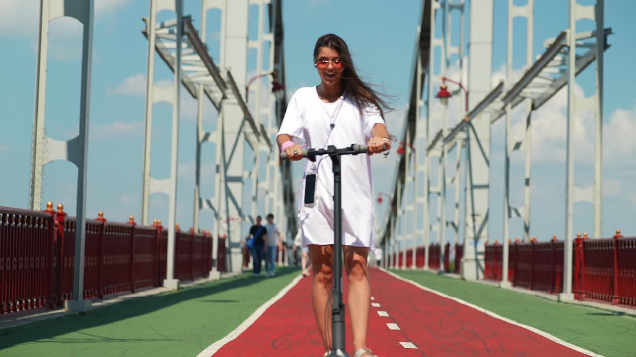 mujer disfrutando de un paseo en scooter eléctrico en un puente de la ciudad