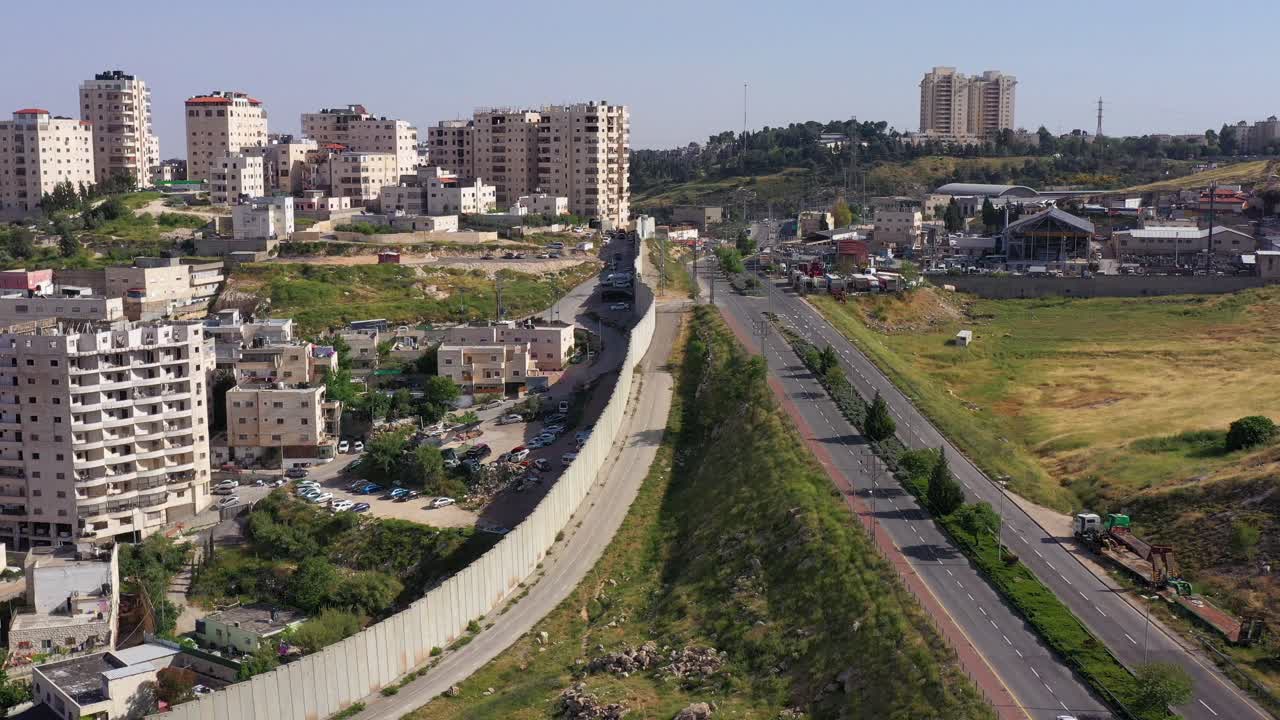 Aerial view of a city divided by a separation wall with a highway