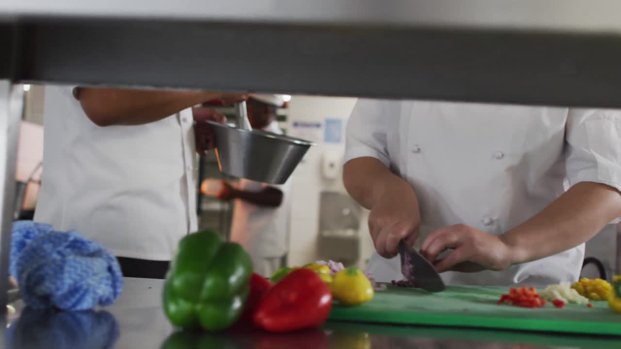 sección media de un grupo diverso de chefs preparando comida en la cocina de un restaurante