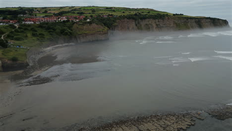 establishing aerial drone shot of robin hood's bay at low tide o misty morning