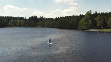 a lone young man enjoying smooth calm waters while out paddling a sup, aerial orbit