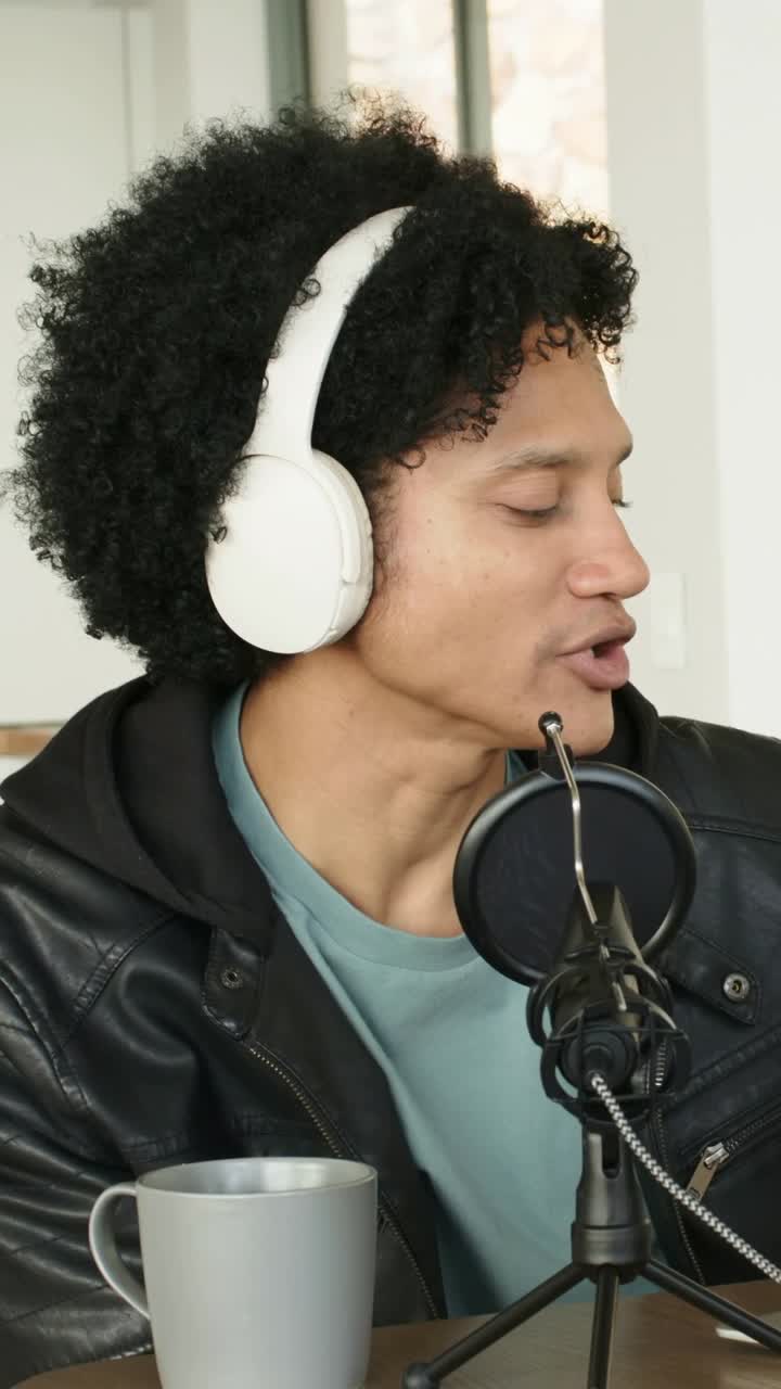 Video verticale: Conduttore parla con cuffie, registra un podcast in studio, regola l'asta del microfono.