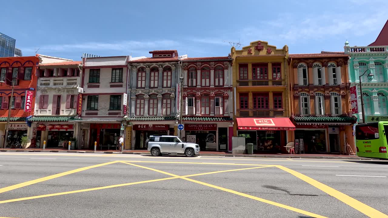 Daytime cityscape with trucks driving past colorful heritage shophouses in Singapore’s Chinatown district