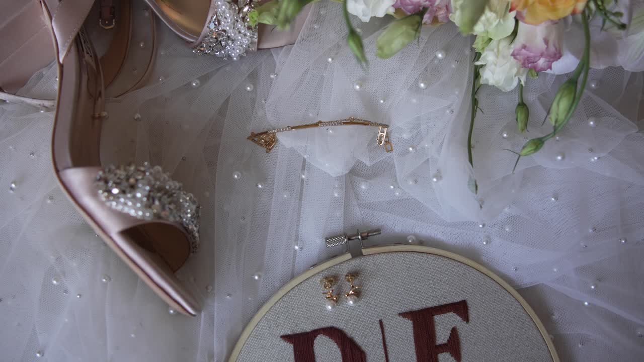 Elegant bridal shoes, jewelry, and floral accents arranged on delicate fabric