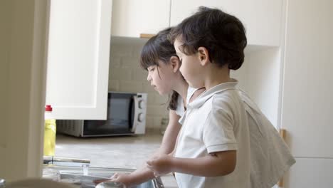 Two-cute-little-kids-washing-dish-in-kitchen