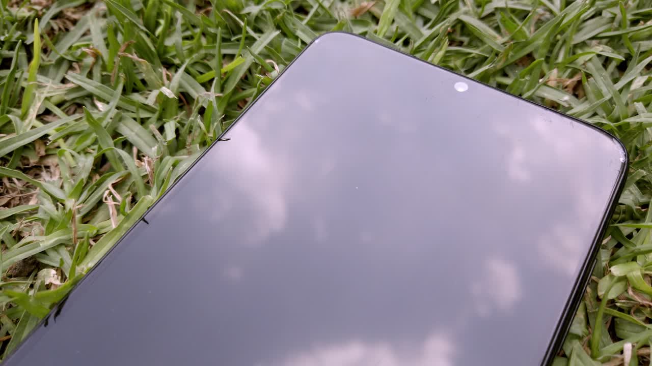 Phone on grass reflecting sky, close-up with calm, dreamy and natural mood