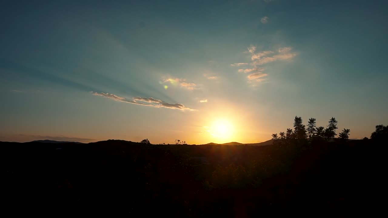 puesta de sol brillante alcanzando su punto máximo a través de colinas con nubes en el cielo azul en el parque forestal de españa