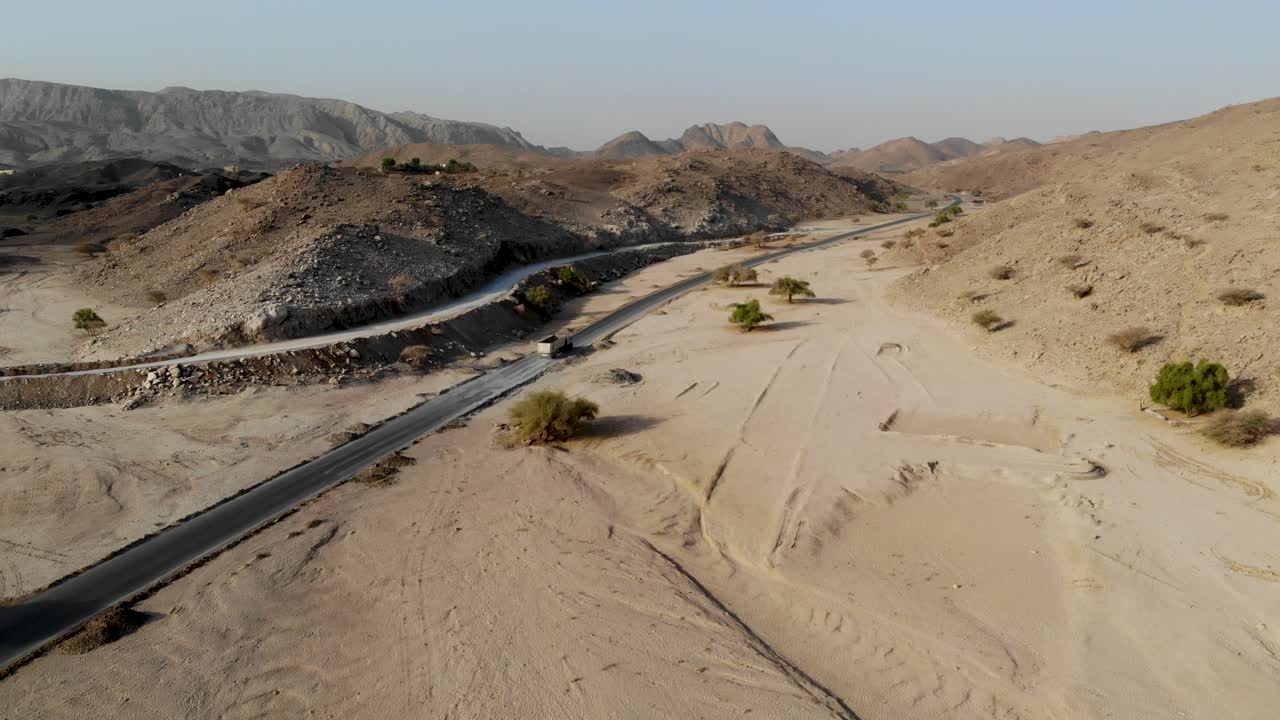 트레일러를 탑재한 화물차가  비어 있는 고속도로를 가로질러 운전하고 있다. 아랍에미리트 푸자이라에서 아침 일찍 비어 있는 땅과 산으로 둘러싸인 곳이다.