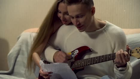 couple playing guitar together at home