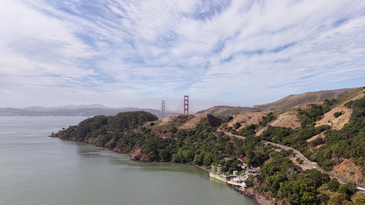 Panoramatický letecký pohled na ikonický most Golden Gate a malebné pobřeží Marin Headlands v San Franciscu, Kalifornie, pod částečně zataženou oblohou během slunečného dne