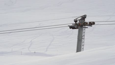 Empty-ski-lift-running-up-and-down-with-snow-covered-mountain-hills-seen-in-background