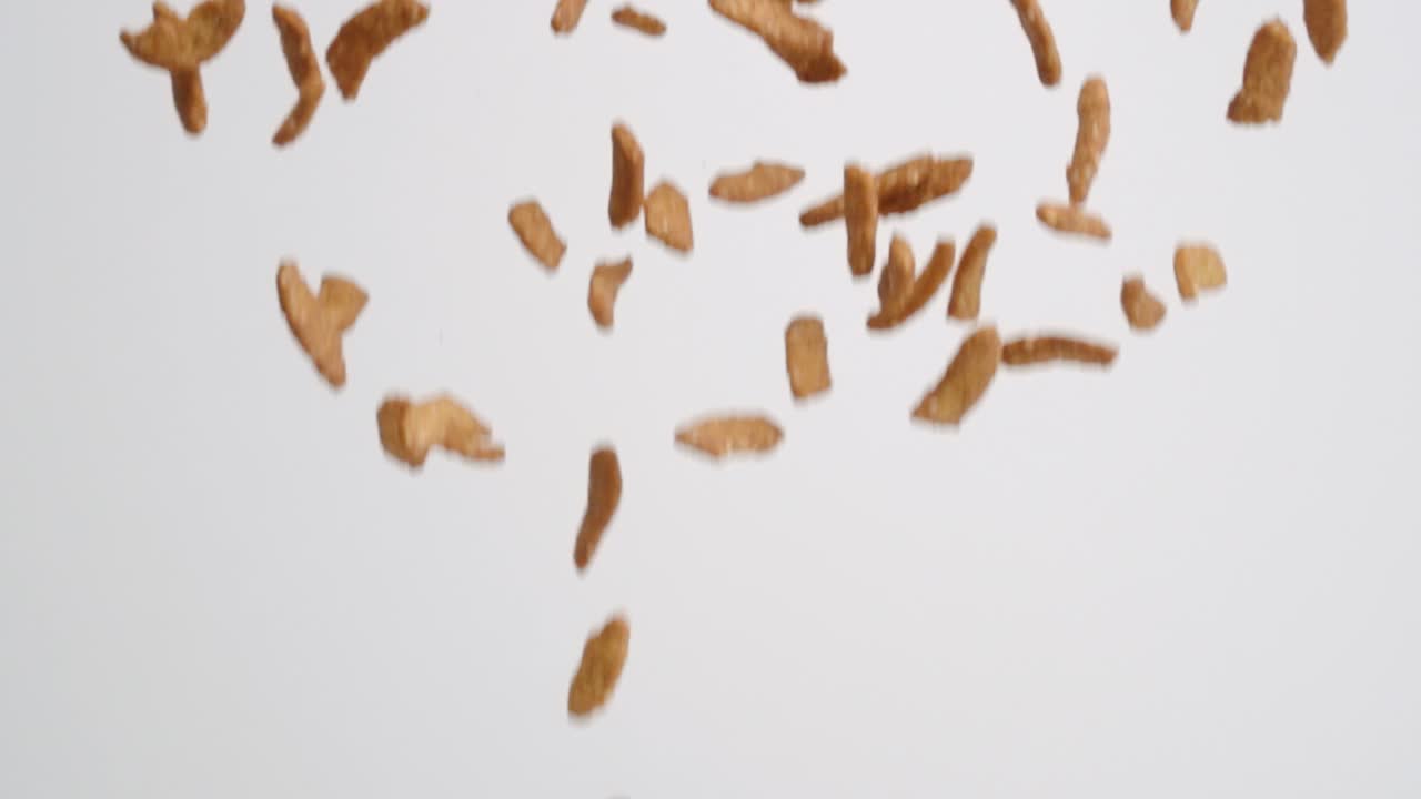 Pezzi di snack salati a bastoncino al sesamo che scendono a pioggia su sfondo bianco al rallentatore