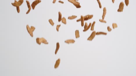 Salty-sesame-stick-snack-pieces-raining-down-on-white-backdrop-in-slow-motion