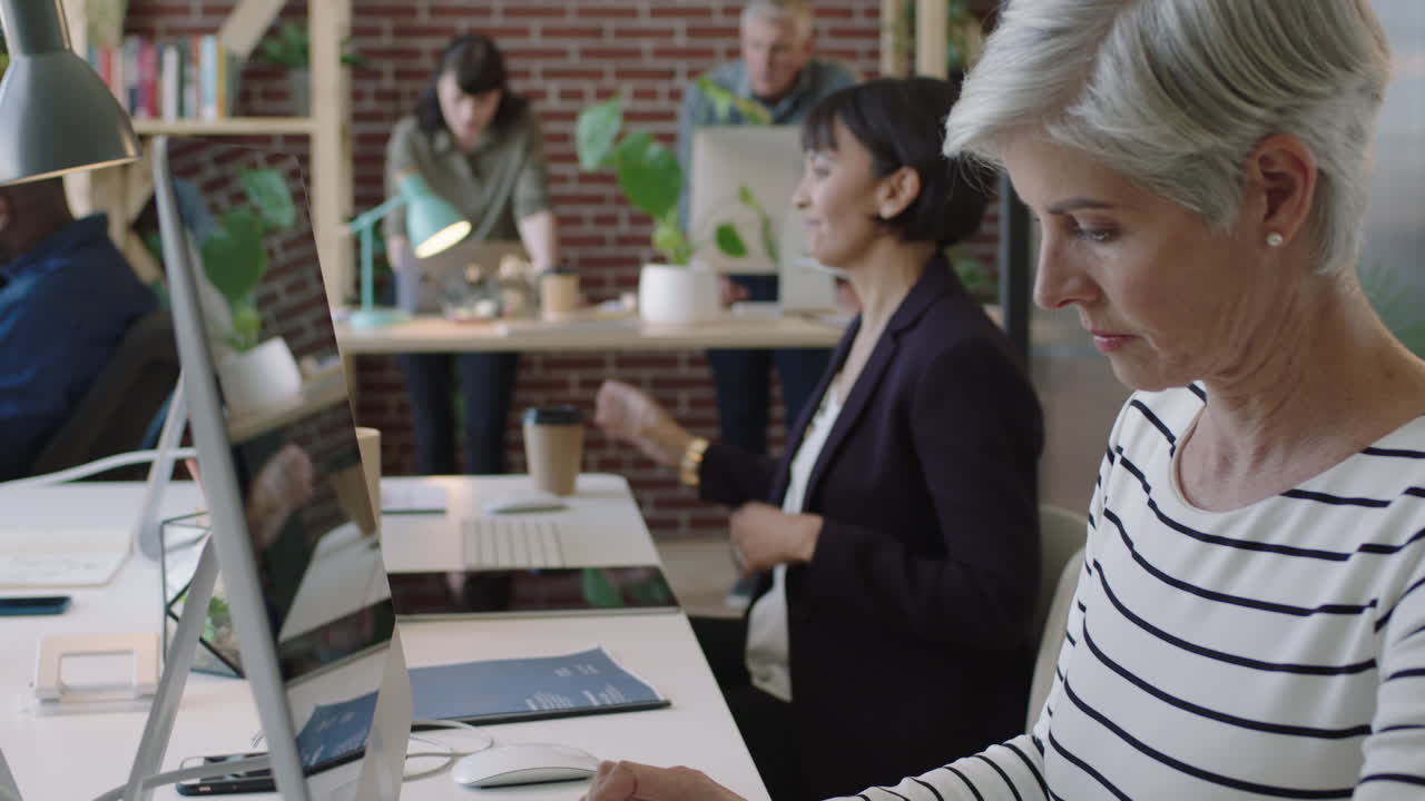 다양한 사무실 작업 공간에서 컴퓨터 네트워크를 사용하는 성숙한 사업주 여성 스타트업 프로젝트에서 일하는 동료 창의적인 다민족 전문 팀