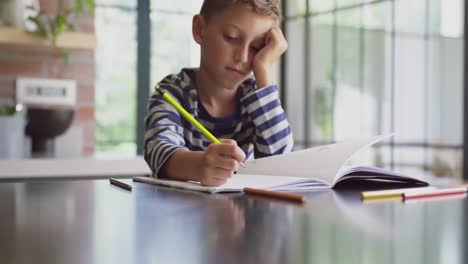 boy studying at table in kitchen at home 4k