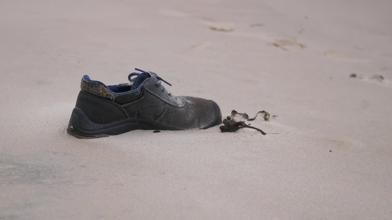 zapato viejo en la playa, basura y basura en una playa vacía de arena blanca del mar báltico, problema de contaminación ambiental, día nublado, toma de primer plano medio