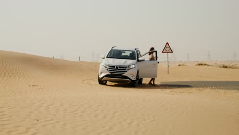 woman standing by a car in the desert