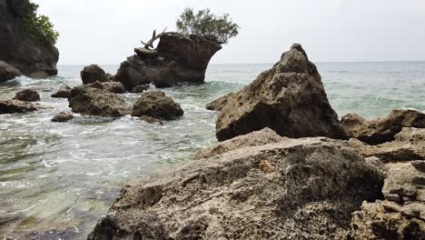 una playa rocosa y una formación rocosa natural con olas suaves y una ubicación remota