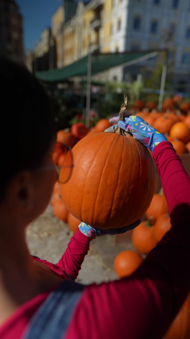 mujer recogiendo una calabaza en un mercado de otoño