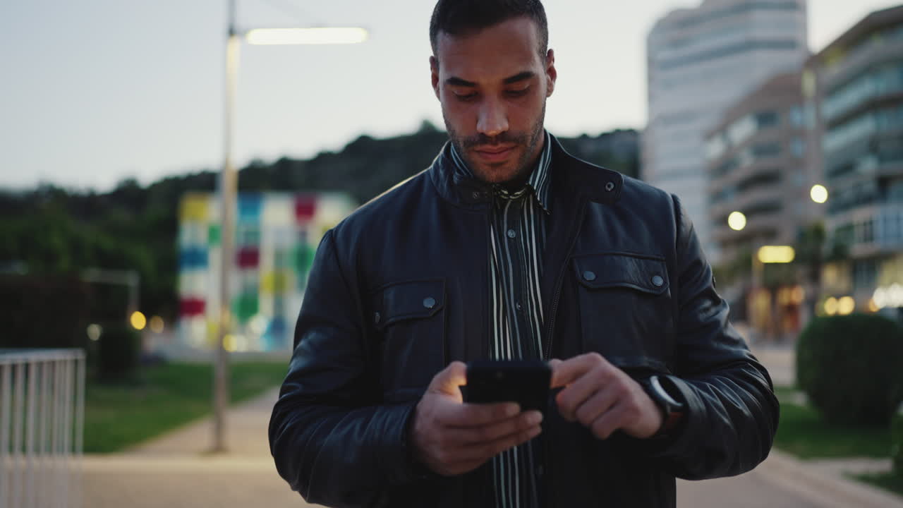 Young man using smartphone and walking outdoors.