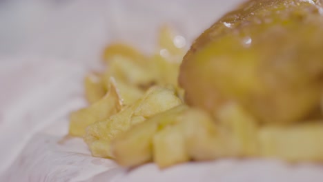 close-up einer person, die eine traditionelle britische mahlzeit mit fisch und chips mit den fingern isst