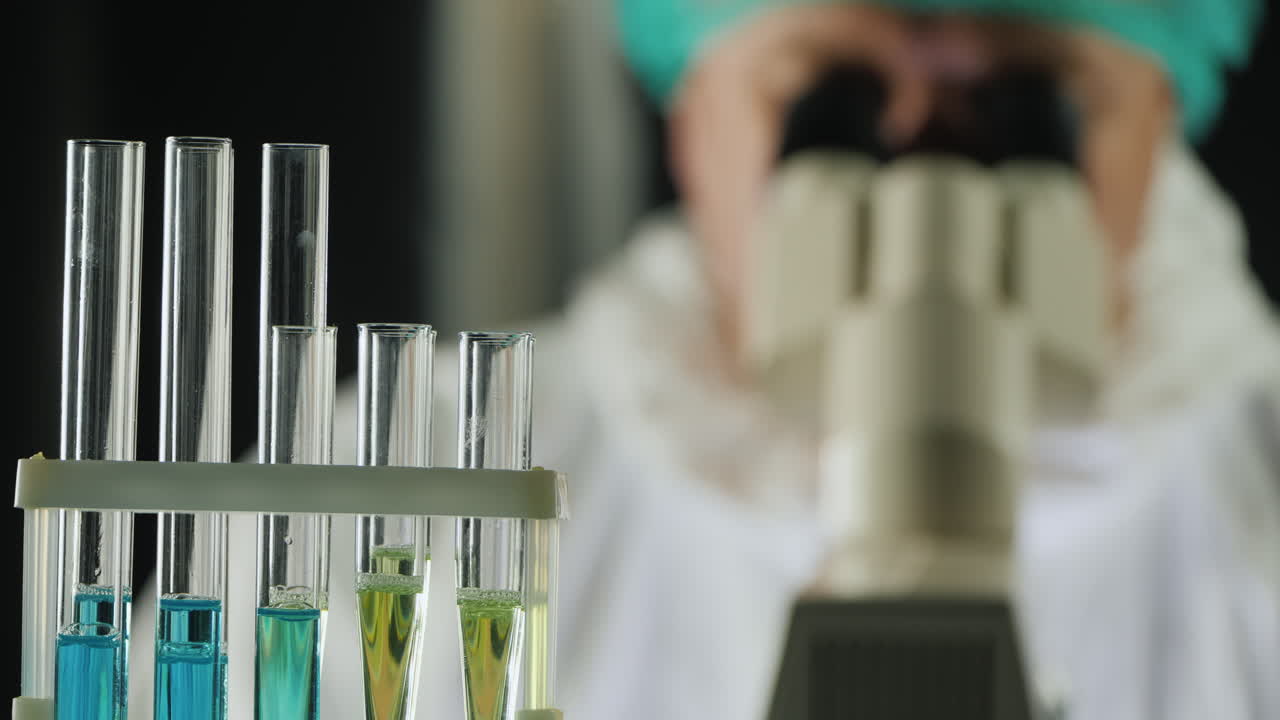 tubos de ensayo en el laboratorio mientras un hombre trabaja con un microscopio 1