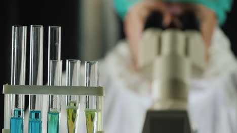 tubos de ensayo en el laboratorio mientras un hombre trabaja con un microscopio 1
