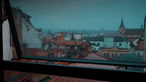 Raindrops-Falling-on-a-Glass-Window-in-the-City-Center-of-Prague,-Czech-Republic-on-a-Cloudy-Day-with-the-City-in-the-Background