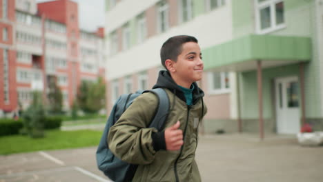 Vista lateral de un niño pequeño corriendo con una mochila y mirando de reojo mientras sube escalones, con un edificio residencial borroso al fondo y una expresión que denota determinación y energía juvenil