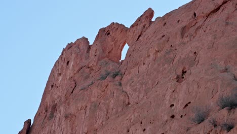 close-up of rugged red sandstone rock wall featuring a natural arch formation at garden of the gods, colorado