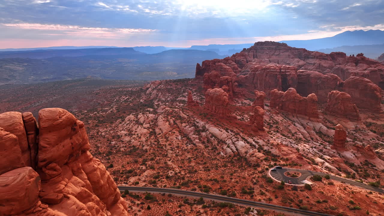 Sorvolo delle cime arrotondate di rocce arancioni al tramonto. Avvicinamento all'autostrada e alla piattaforma panoramica nell'Arches National Park nello Utah, USA. Prospettiva aerea