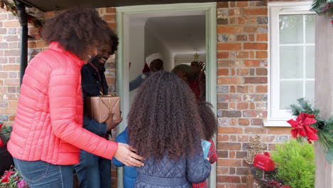 grandparents greeting family as they arrive for visit on christmas day with gifts