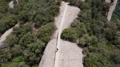 mujer joven caminando por el parque nacional de la montaña de montserrat, barcelona, españa, disparo de avión no tripulado, vista de ojo de águila, concepto de bienestar, deporte y naturaleza