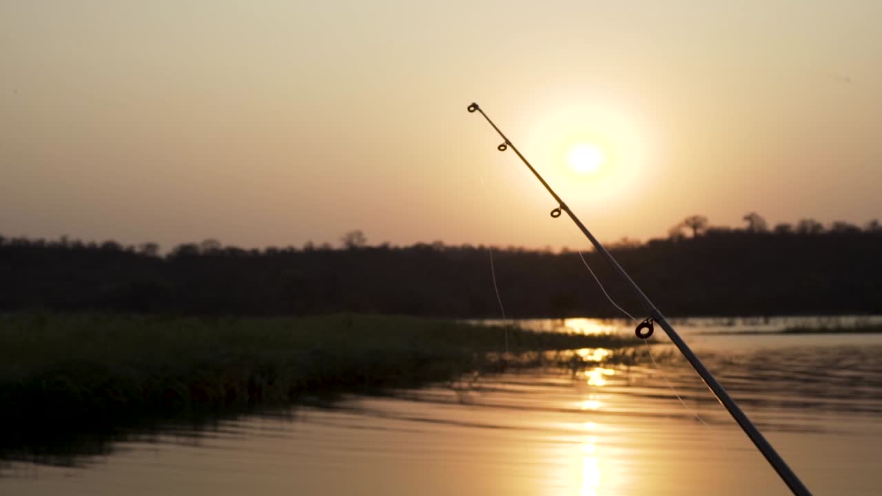 Bidikan lebar pancing di sungai saat matahari terbenam yang indah.