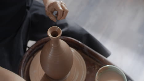 pottery artist shaping a vase on a potter's wheel