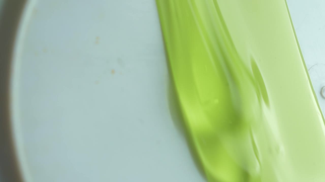 Jelly-like Fluid Gel Dripping Against White Surface. Closeup