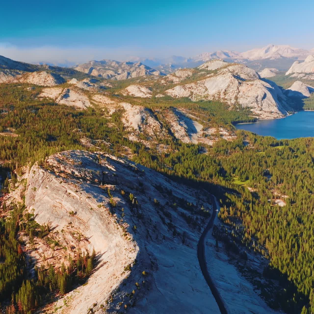 Yosemite National Park scenery in the rays of hot bright sun. Beautiful rocks, pine tree woods and lakes in the panorama of famous park from aerial view