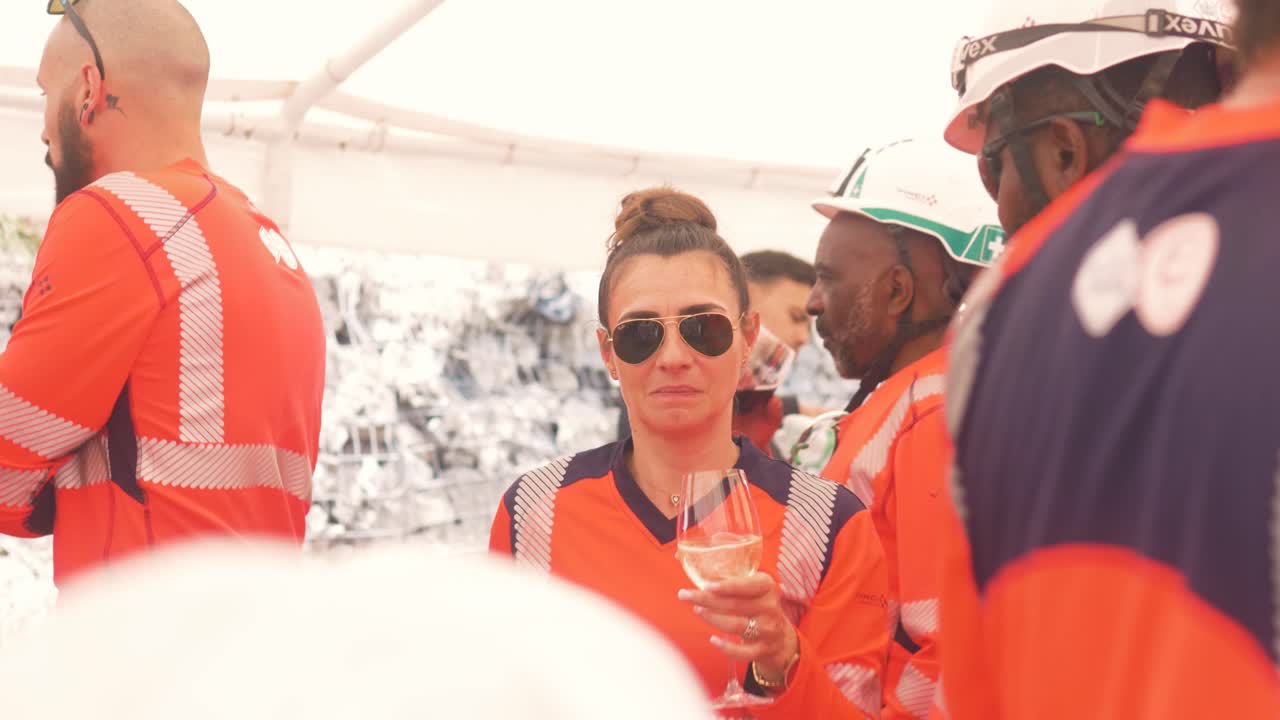 Workers in safety gear collaborate on bridge rigging under bright sunlight at a construction site