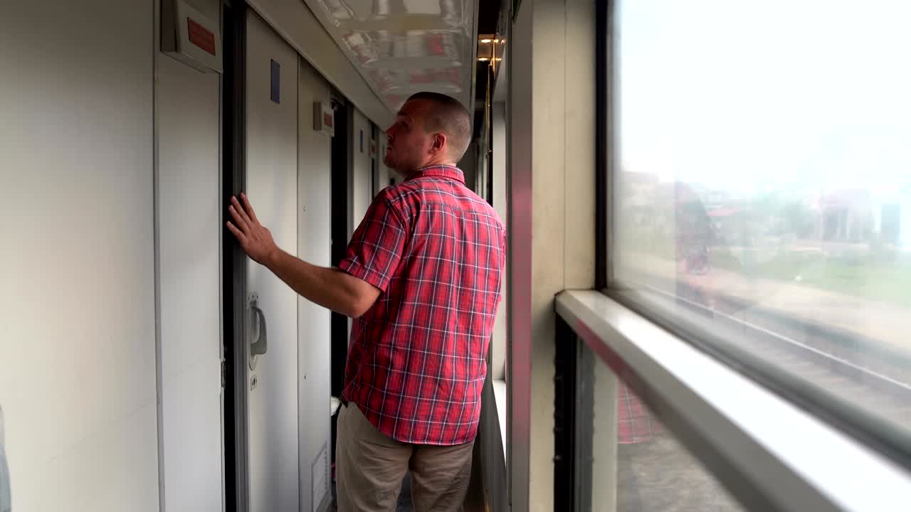 un hombre sale del compartimento del tren y va al vestíbulo