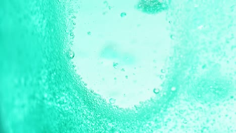 macro shot of bright blue water with many sparkling bubbles leaving a little spot without bubbles